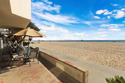 a table with chairs and an umbrella on the beach at Seashore Sun and Fun - On Beach in Newport Beach