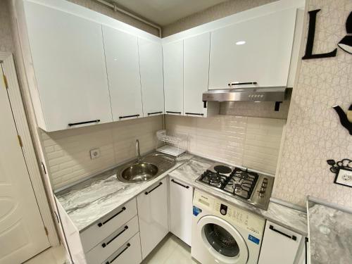 a small kitchen with white cabinets and a sink at квартира на аренду in Sumqayyt