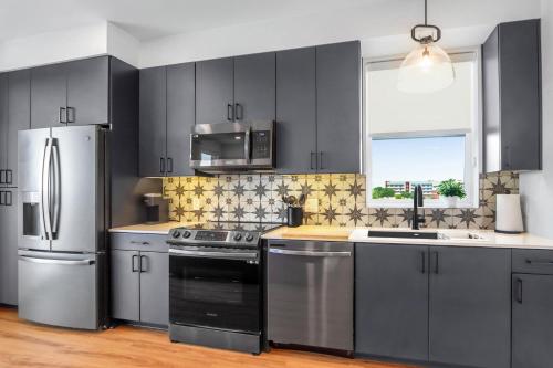 a kitchen with black cabinets and stainless steel appliances at Creekside Modern - Condo for 4 in New Braunfels