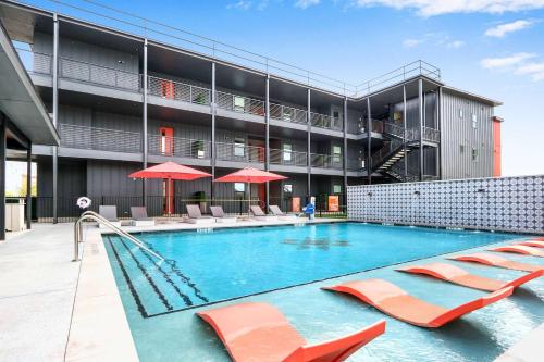 a large swimming pool with chairs and a building at Creekside Modern - Condo for 4 in New Braunfels