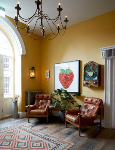 a living room with leather chairs and a painting of a strawberry at Artist Residence Bristol in Bristol