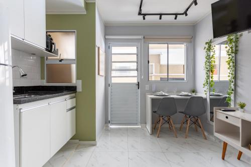 a kitchen with white cabinets and a table and chairs at Manacá Studio Praticidade e Estilo na Aclimação in Sao Paulo