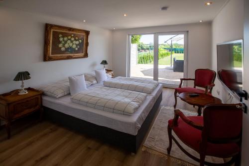 a bedroom with a bed and two red chairs at Apartman louis A102 in Tomášikovo