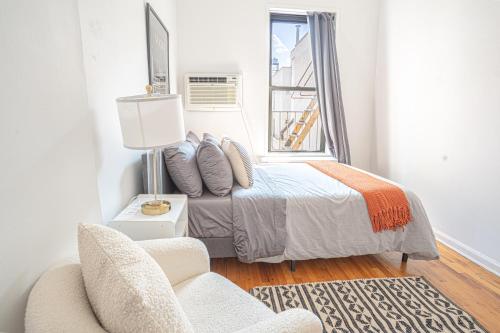 a bedroom with a bed and a chair and a window at Chic 2BD Upper East Side Retreat in New York
