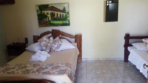 a bedroom with two beds and a painting on the wall at Recanto das Águas in Britânia