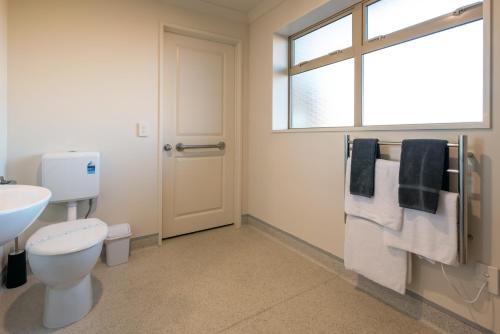 a bathroom with a toilet and a sink and a window at Hanmer Springs Gateway Lodge in Hanmer Springs