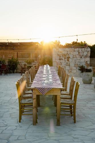 a wooden table with chairs around it with the setting sun at Masseria della Piana in Villanova di Ostuni