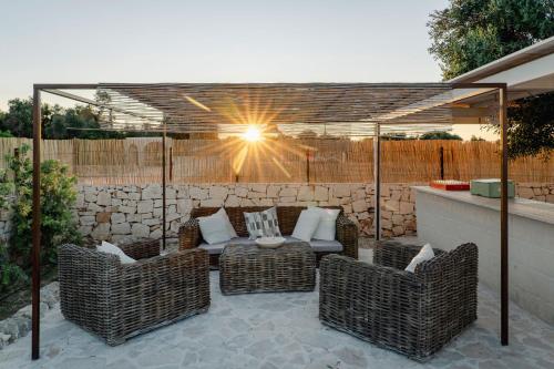 acovered patio with wicker chairs and a table at Masseria della Piana in Villanova di Ostuni