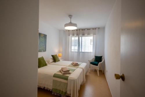 Un dormitorio blanco con una cama y una silla. en Comeback A un Suspiro del Mar, en La Herradura