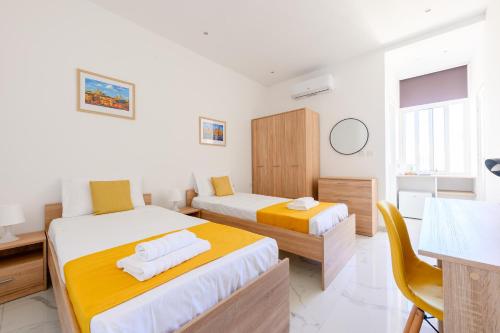 a bedroom with two beds and a desk and a kitchen at F8-4 Sliema ensuite bedroom in Sliema