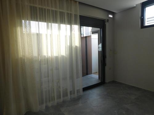a room with a window and a door with curtains at Kalon Gaia NOSTOS in Karistos