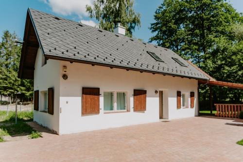 a small white house with a black roof at Buškovský mlýn 1580 in Dolní Bousov