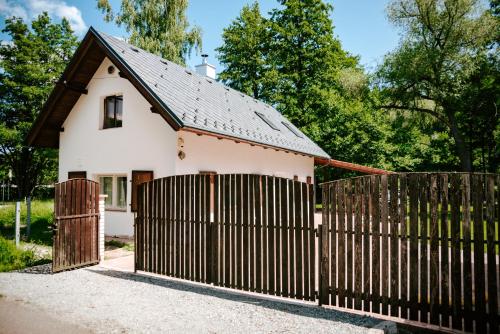a small white house with a wooden fence at Buškovský mlýn 1580 in Dolní Bousov