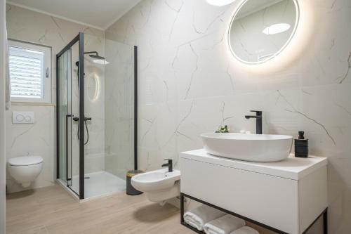 a white bathroom with a sink and a toilet at Villa Senka in Rogotin