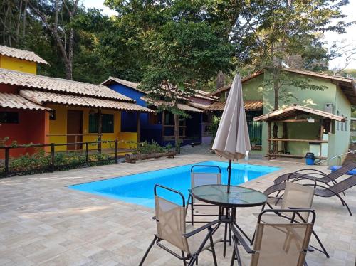 a table with an umbrella next to a pool at Pousada Cigarras da Serra in Serra do Cipo