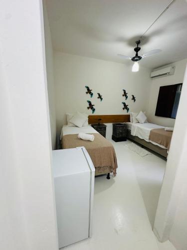 a white room with two beds and a tv at Pousada Amor de Casa in Trancoso