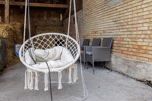 a white swinging chair sitting next to a brick wall at Uelis-Stoeckli Gästezimmer mit Billard und Lamatrekking in Meikirch