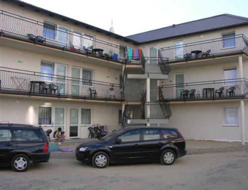 two cars parked in a parking lot in front of a building at Apartamenty Afrodyta in Karwia
