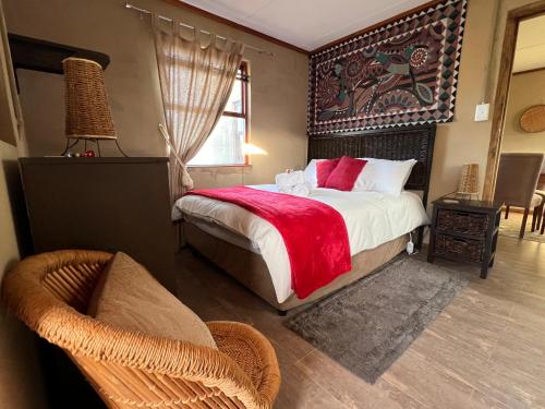 ein Schlafzimmer mit einem Bett und einem Stuhl und einem Fenster in der Unterkunft Renewal Retreat Klein Karoo Cottage in Uniondale