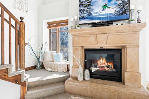 a living room with a fireplace with a tv above it at Calming Canyons - Ski-in Ski-out Luxe Penthouse in Park City