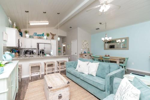 a living room with a blue couch and a kitchen at Fun 4 Bedroom - Resort Pool Sleeps 12 in Port Aransas
