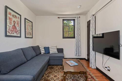 a living room with a blue couch and a tv at Garden Cottage at Miramar Beach with Shared Deck in Montecito