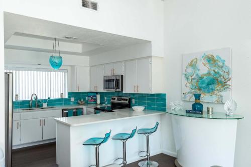 a kitchen with white cabinets and blue tile at Stylish 3 bedroom - Pool Pets Sleeps 10 in Port Aransas