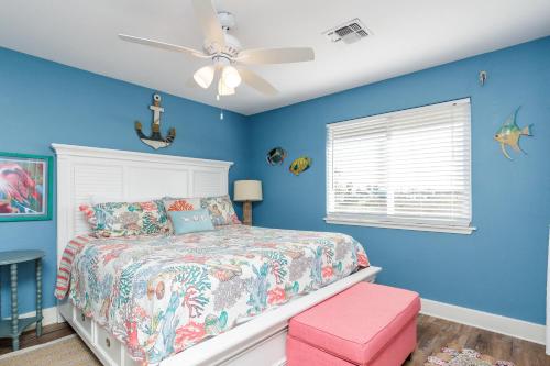 a blue bedroom with a bed and a ceiling fan at The Oasis - Pet Friendly Optional Golf Cart in Port Aransas
