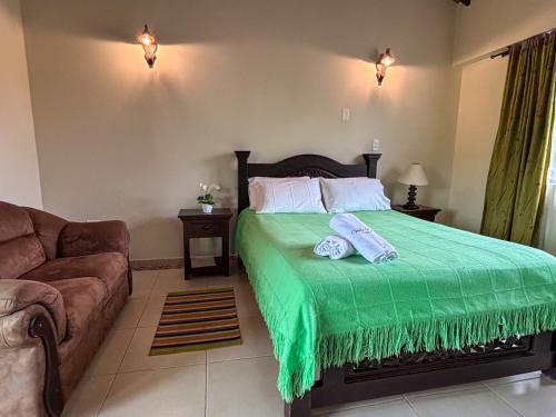 a bedroom with a bed with a green blanket at Hotel Villa Sofia in Nobsa