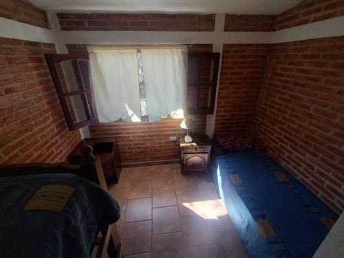 a bedroom with a brick wall and a window at Cabañas Guer Aike in Villa Carlos Paz