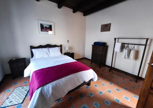 Un dormitorio con una cama con una manta morada. en Casa Real de Mexicanos, en San Cristóbal de Las Casas