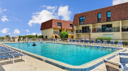 a pool at a hotel with chairs and people in it at Poolfront 2BR Condo with BBQ Steps To Beach & Pier in Cocoa Beach