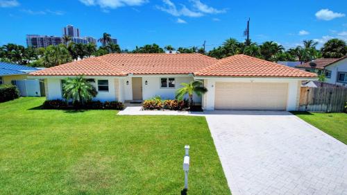 a white house with a garage in a yard at Dolphin Villa - Private Pool in West Palm Beach