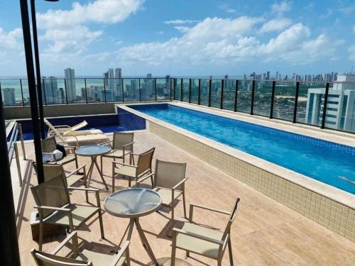 a balcony with chairs and a swimming pool on a building at Beach Class Excelsior - Flat 1 quarto no Pina por Yolo in Recife