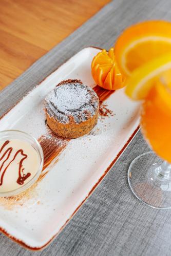 a plate with a chocolate cake and a glass of orange juice at Hotel GOLD JET Bihać in Bihać