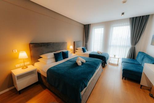 a hotel room with two beds and a blue couch at Hotel GOLD JET Bihać in Bihać