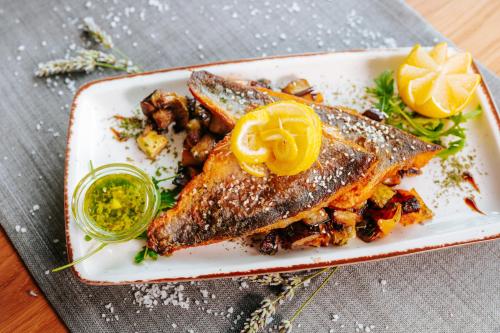 a plate of food with fish and vegetables on a table at Hotel GOLD JET Bihać in Bihać