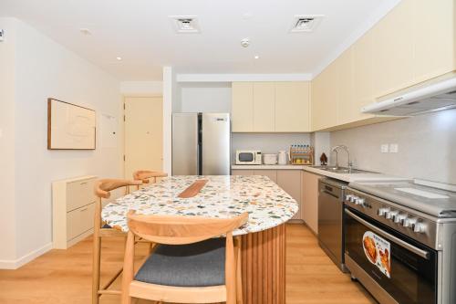 a kitchen with a table with chairs and a counter top at GV Holiday Homes DXB - Cozy 2BR Apartment in Town Square Dubai in Dubai