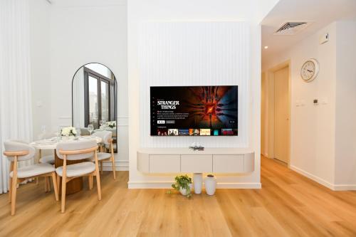 a living room with a tv on a wall at GV Holiday Homes DXB - Cozy 2BR Apartment in Town Square Dubai in Dubai