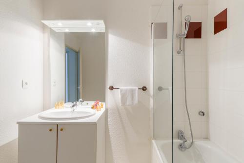 biała łazienka z umywalką i prysznicem w obiekcie Lagrange Vacances Les Terrasses du Lac w mieście Aureilhan