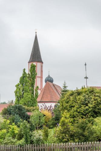 a church with a steeple in the distance behind a fence at Hotel Gasthof Hainzinger in Einsbach