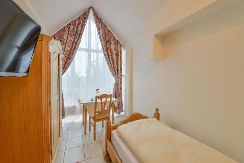 a bedroom with a bed and a table and a window at Hotel Gasthof Hainzinger in Einsbach