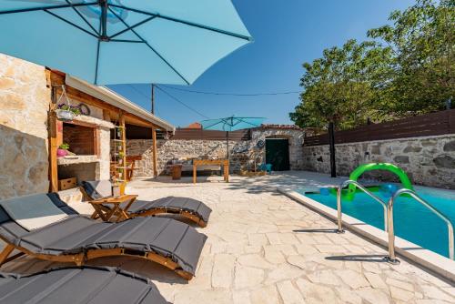 a patio with a swimming pool and an umbrella at Filotea in Smrdelje