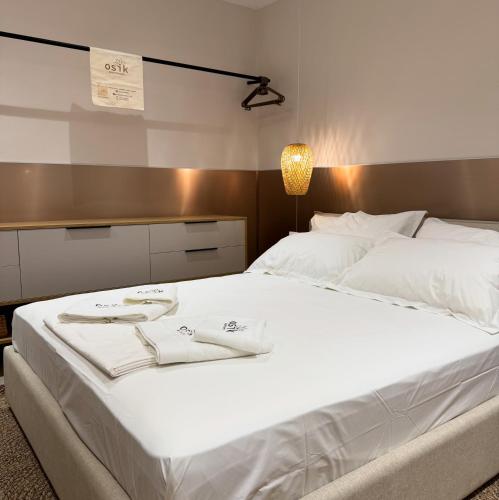 a large white bed with two white towels on it at Osik apartments villa 01 in Golem