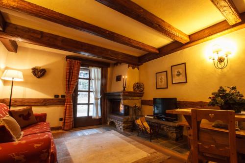 a living room with a couch and a television at Au Coeur Des Neiges Resort SPA & FREE E-BIKE in Courmayeur