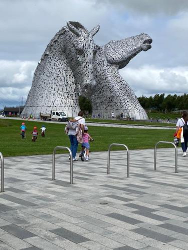 a woman and child walking past a statue of a horse at Caledonia House in Rosyth