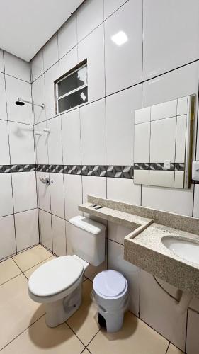 a white bathroom with a toilet and a sink at Hotel Amazonida in Manaus