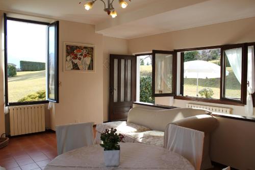 a living room with a couch and tables and windows at Le Betulle in Oggebbio