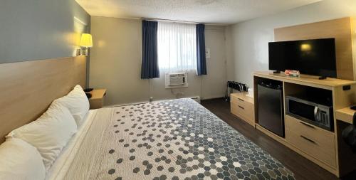 a hotel room with a bed and a flat screen tv at Econo Lodge Motel Village in Calgary