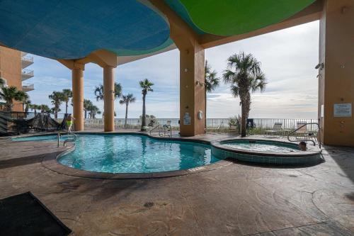 a swimming pool in a resort with palm trees at Beachfront Haven 2 BDR Kid-Friendly Resort in Panama City Beach